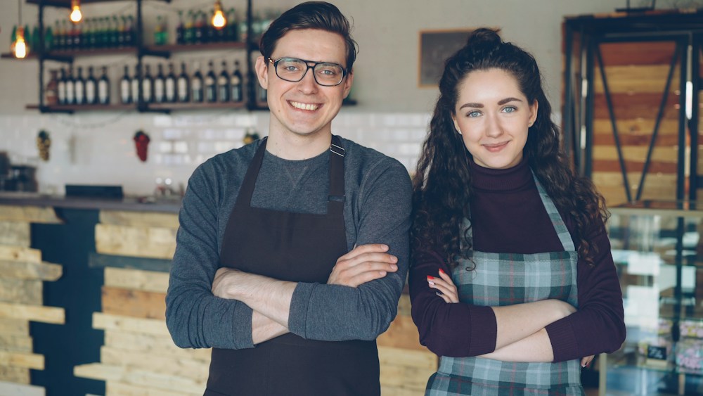 Two cafe owners standing proudly in their shop